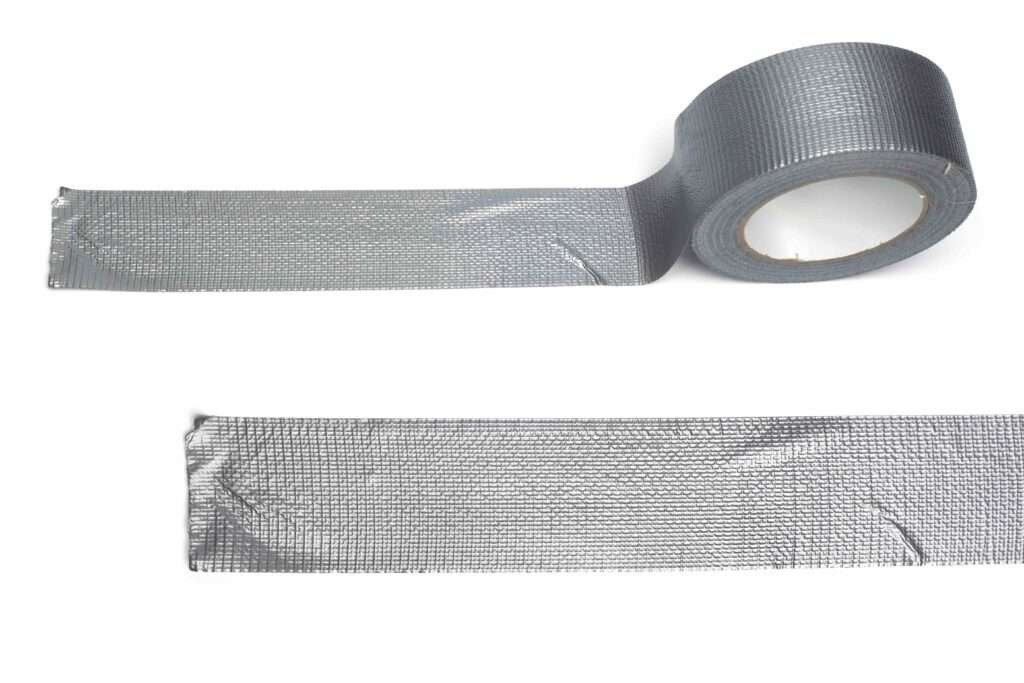 Umzugskartons 23 Umzugsunternehmen Hannover - Eine Rolle silbernes Isolierband ist teilweise abgerollt, darunter liegt ein separater Streifen flach auf einem weißen Hintergrund – ideal, wenn Sie Klebeband in der Nähe von Hannover kaufen möchten. Umzugsunternehmen Seelze.